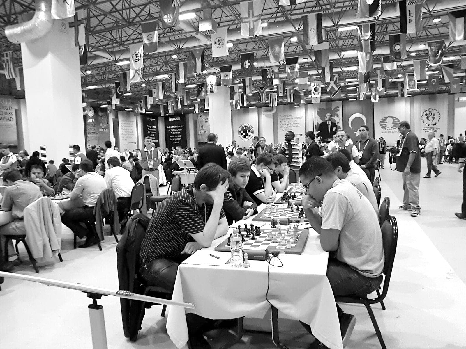 Players at the boards in a national-flag-lined tournament hall